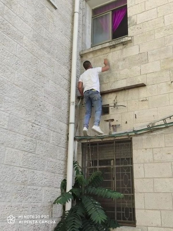 病院の壁をよじ登るジハードさん（画像は『Bored Panda　2020年7月21日付「Man Climbs Up Hospital Wall And Watches Over His Mom From Outside The Hospital Day And Night Until She Dies Due To Coronavirus」』のスクリーンショット）