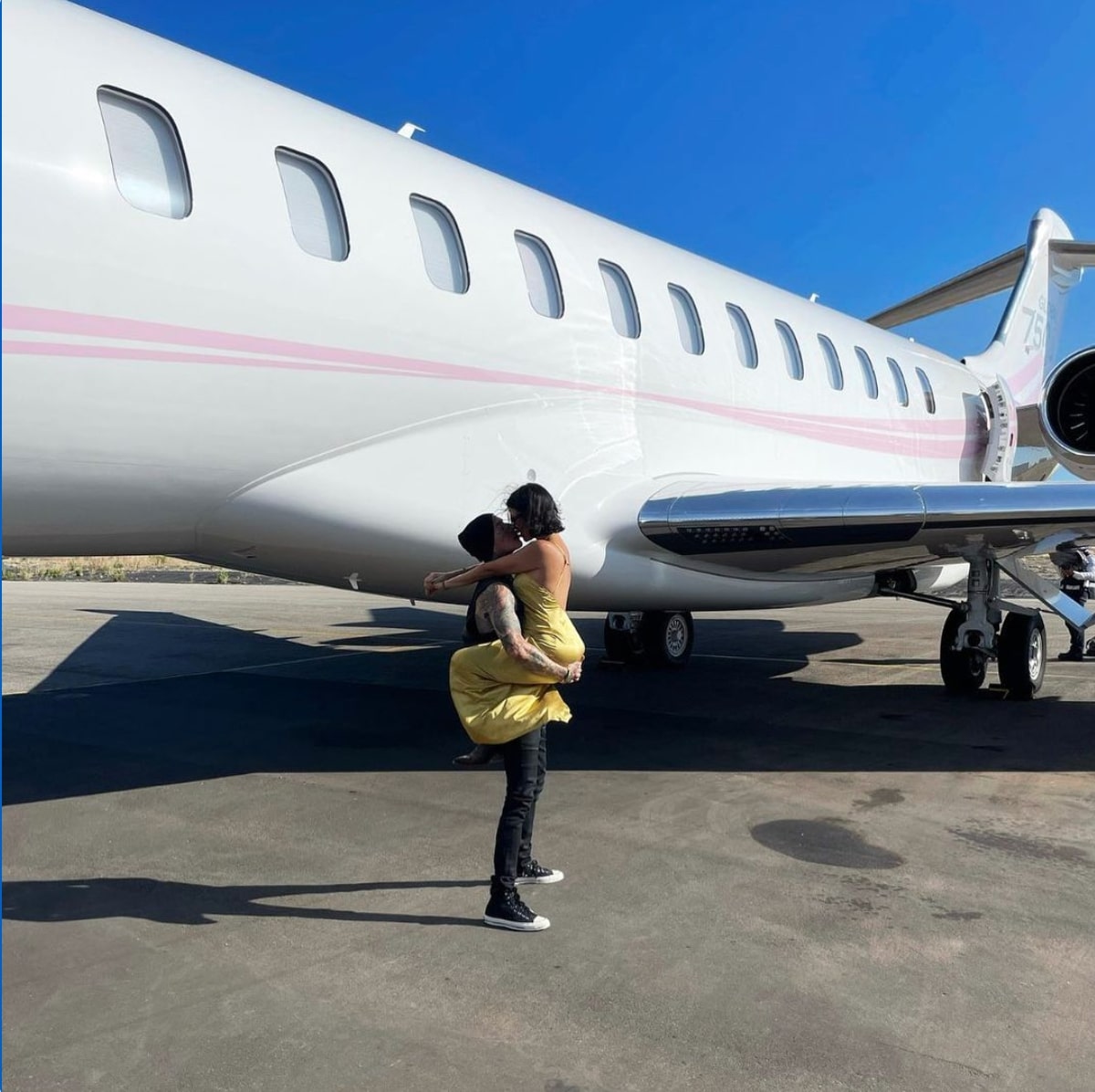 飛行機の前でキスするトラヴィスとコートニー（画像は『travisbarker　2021年8月18日付Instagram「With you anything is possible ＠kourtneykardash」』のスクリーンショット）