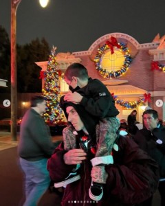 コートニーの息子レイン君を肩車するトラヴィス（画像は『Kourtney Kardashian　2021年12月18日付Instagram「The happiest place on earth, in the rain at Christmas time」』のスクリーンショット）