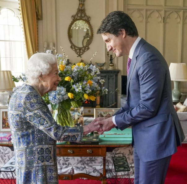 ウクライナ国旗を表す花束の前で握手を交わす女王とトルドー首相（画像は『The Royal Family　2022年3月7日付Instagram「This afternoon The Queen received the Prime Minister of Canada, ＠justinpjtrudeau, for an Audience at Windsor Castle.」』のスクリーンショット）