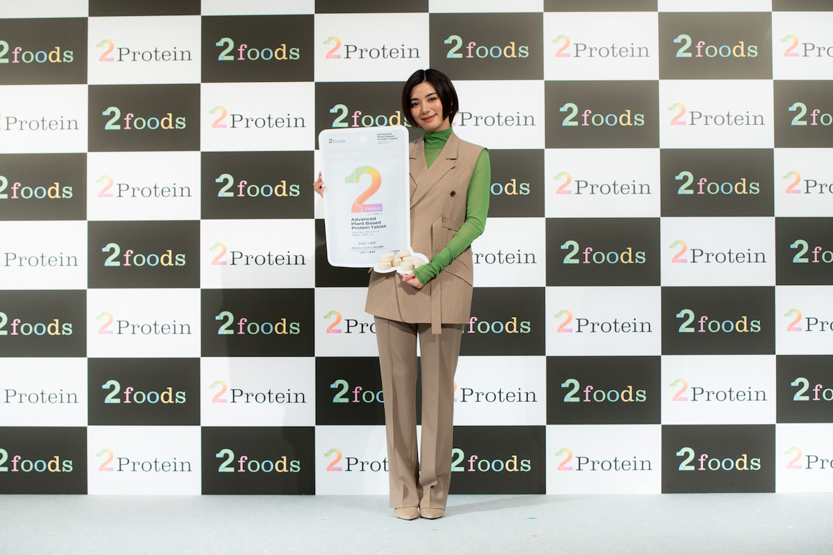 巨大化した新商品「2Protein」のパッケージを手に写真撮影に応じる池田エライザ。本物はサイズ感もコンパクトで気に入っているという