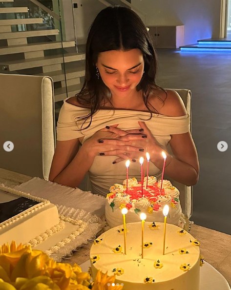 キャンドルを立てたケーキを前にするケンダル・ジェンナー。両手を合わせて目を閉じ、願い事を捧げている（画像は『Kendall　2023年11月4日付Instagram「twenty ate」』のスクリーンショット）