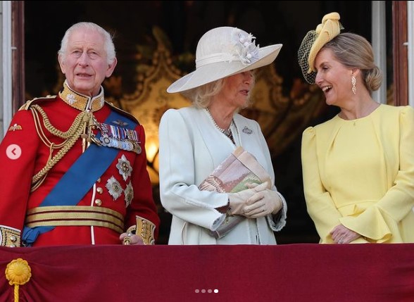 バルコニーでソフィー妃と談話するカミラ王妃。王妃は淡いブルーの帽子とドレスを着ている（『The Royal Family　Instagram「The King, Queen and other Members of the Royal Family are greeted by crowds as they gather on the balcony of Buckingham Palace to watch the traditional fly-past.」』より）